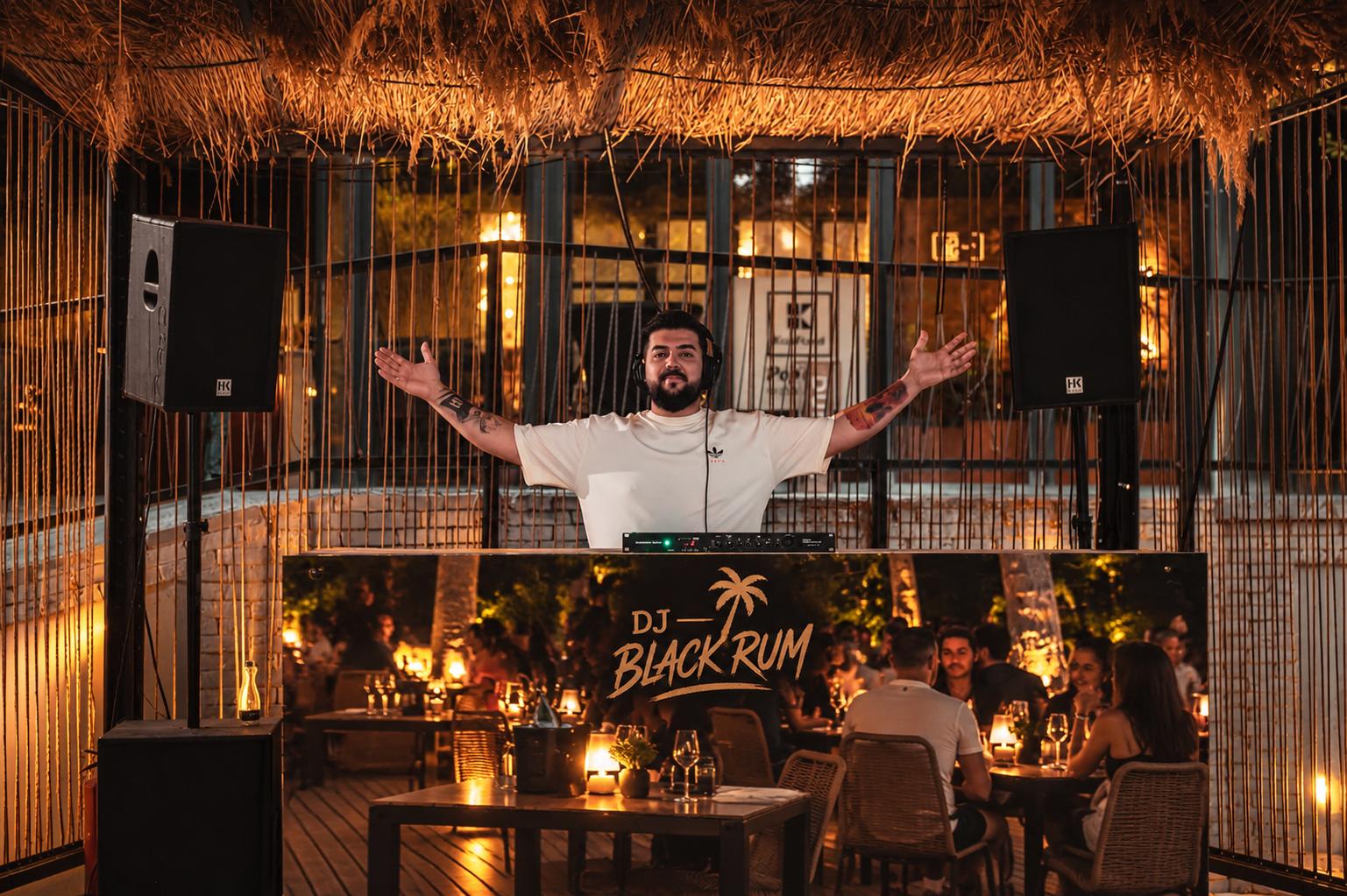 DJ Black Rum cu brațele deschise, în fața standului cu logo